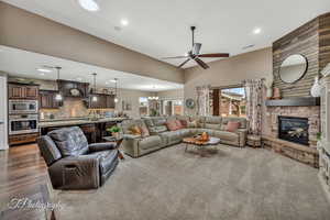 Living room featuring sink, a stone fireplace, and ceiling fan with notable chandelier