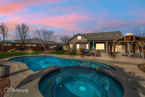 Pool at dusk featuring an in ground hot tub, a gazebo, and a patio area