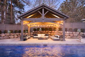 Pool at dusk featuring an outdoor living space, a gazebo, and a patio