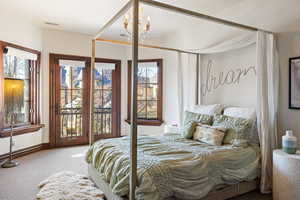 Carpeted bedroom featuring access to outside and an inviting chandelier