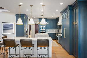 Kitchen with hanging light fixtures, high end appliances, blue cabinetry, and a spacious island