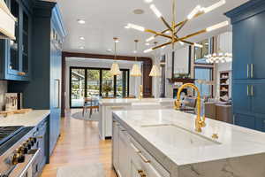 Kitchen featuring a large island, decorative light fixtures, light stone countertops, and a chandelier