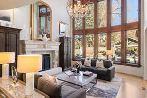 Living room featuring a tiled fireplace, light parquet floors, and a high ceiling