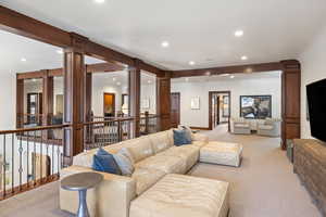 Carpeted living room featuring ornate columns and beamed ceiling