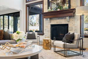 Living room with wood-type flooring, a stone fireplace, and a healthy amount of sunlight