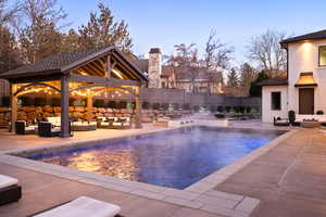 Pool at dusk with a gazebo, an outdoor hangout area, and a patio
