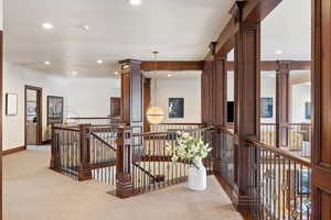 Hall featuring carpet flooring and decorative columns