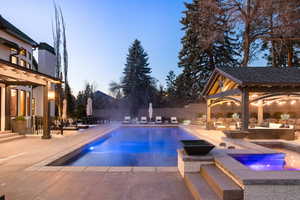 Pool at dusk with an in ground hot tub, a patio, an outdoor living space, and a gazebo