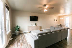 Living room with ceiling fan, a textured ceiling, wood-type flooring, and a healthy amount of sunlight