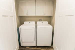 Clothes washing area featuring dark hardwood / wood-style floors, cabinets, and washing machine and clothes dryer