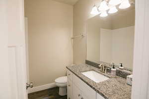 Bathroom with vanity, hardwood / wood-style flooring, and toilet