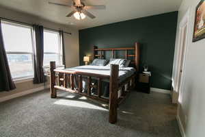 Carpeted bedroom with ceiling fan and a textured ceiling