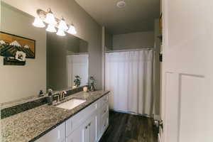 Bathroom with vanity, curtained shower, hardwood / wood-style floors, and an inviting chandelier