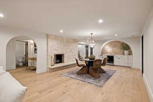 Dining room with a stone fireplace, beverage cooler, and light hardwood / wood-style floors