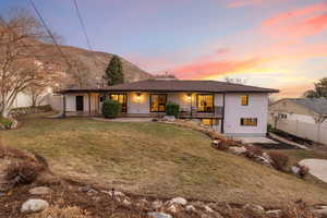 Back house at dusk featuring a lawn