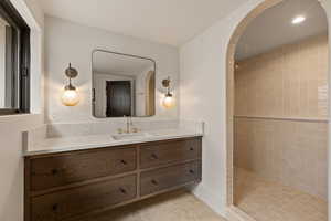 Bathroom with vanity, tile patterned flooring, and a tile shower