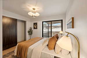 Bedroom featuring access to exterior, hardwood / wood-style flooring, and a chandelier