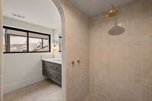 Bathroom featuring tile patterned floors, vanity, and a tile shower