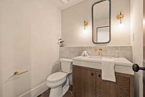 Bathroom featuring vanity, tile walls, and toilet