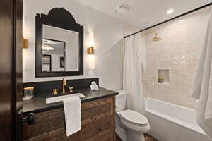 Full bathroom with vanity, shower / bath combination with curtain, and toilet