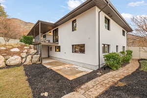 Rear view of property with a balcony, a mountain view, and a patio area