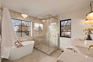 Bathroom featuring shower with separate bathtub, sink, and a wealth of natural light