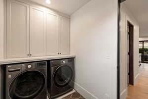 Laundry area featuring cabinets, washer and clothes dryer, and light hardwood / wood-style floors