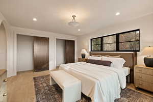 Bedroom with two closets and light hardwood / wood-style flooring