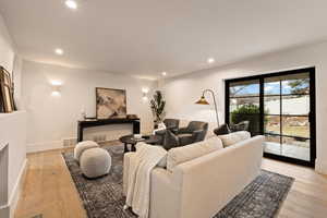 Living room with a fireplace and light hardwood / wood-style flooring