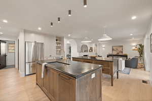 Kitchen featuring white cabinetry, a spacious island, high quality fridge, and pendant lighting