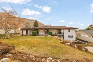 Back of property featuring a mountain view, a yard, and a patio area