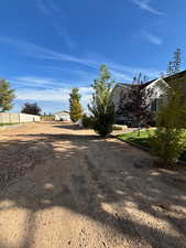 Summer view of trees that line the property and gravel/dirt access to 2 car garage on property and additional parking.