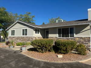 View of front of home with forced air furnace and central air unit on home - Summer View