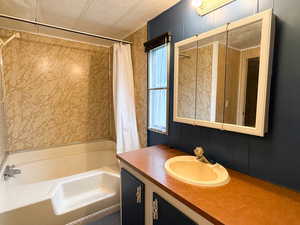 Bathroom with vanity, shower / bath combo, and a textured ceiling