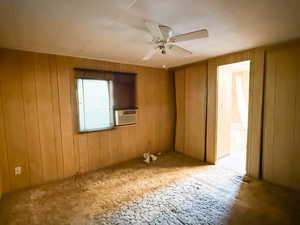 Spare room featuring wooden walls, cooling unit, and ceiling fan