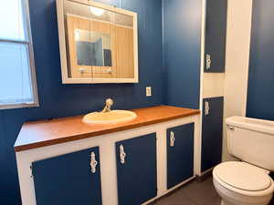 Bathroom featuring plenty of natural light, toilet, tile patterned flooring, and vanity