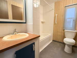 Full bathroom with backsplash, tiled shower / bath combo, vanity, toilet, and tile patterned floors