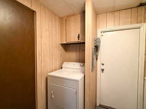 Washroom with cabinets, washer / dryer, and wood walls