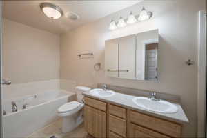 Bathroom with vanity, tile patterned floors, a tub, and toilet