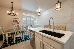 Kitchen featuring a center island with sink, stainless steel dishwasher, sink, and pendant lighting