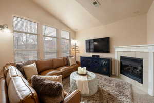 Living room featuring lofted ceiling, carpet flooring, and a tile fireplace