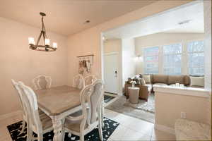 Dining space with light tile patterned floors and a chandelier