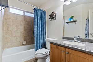 Full bathroom featuring toilet, vanity, and shower / bathtub combination with curtain