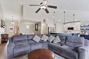 Living room featuring hardwood / wood-style flooring, ceiling fan, and high vaulted ceiling