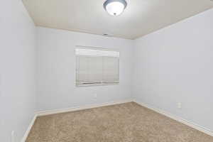 Unfurnished room featuring carpet and a textured ceiling