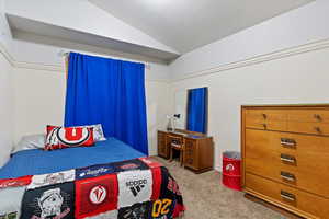 Bedroom with light colored carpet and lofted ceiling