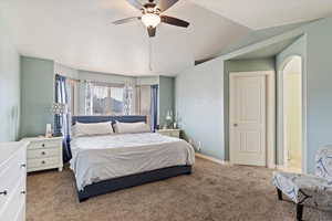 Carpeted bedroom with vaulted ceiling and ceiling fan