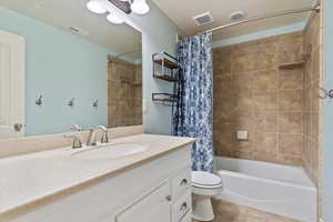 Full bathroom with shower / tub combo, vanity, toilet, and tile patterned flooring