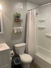 Full bathroom with vanity, hardwood / wood-style flooring, toilet, and shower / bath combo with shower curtain