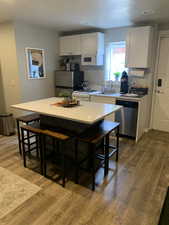 Kitchen with a kitchen bar, a kitchen island, white cabinets, and appliances with stainless steel finishes